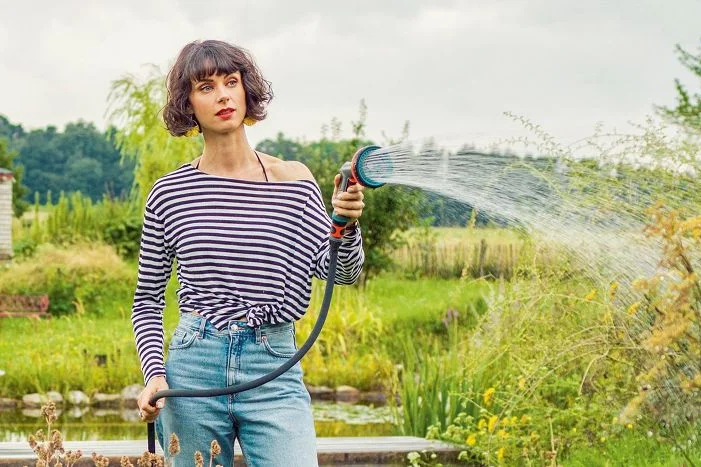 Person gießt mit Schlauch Garten